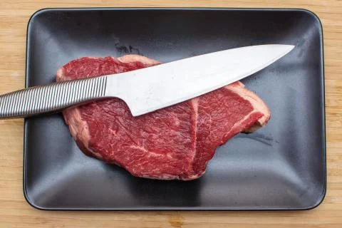 Raw beef on a black plate. Stock Photos
