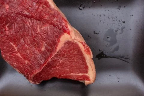 Raw beef on a black plate. Stock Photos