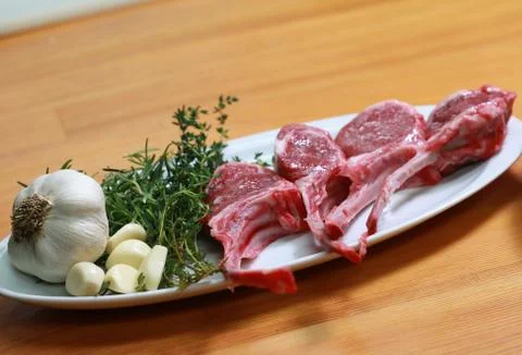 Raw beef bone rib-eye steak on a plate with onion, garlic and garnish Stock Photos