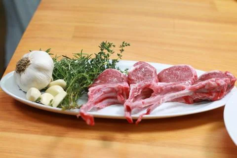 Raw beef bone rib-eye steak with onion, garlic and garnish ready to cook Stock Photos