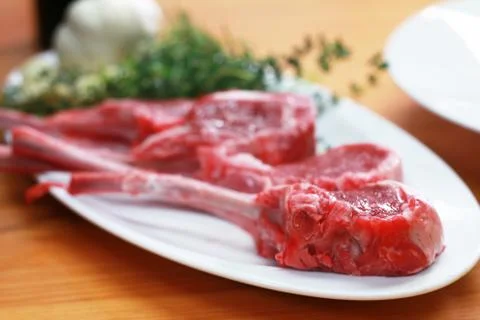 Raw beef bone rib-eye steak on a plate with onion, garlic and garnish Stock Photos