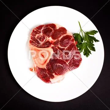 Raw beef with bone on white plate Stock Photos
