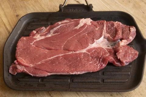 Raw beef chuck steak on cast iron griddle Stock Photos