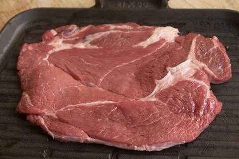 Raw beef chuck steak on cast iron griddle Stock Photos
