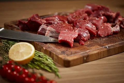 Raw beef cubes on cutting board with knife Stock Photos
