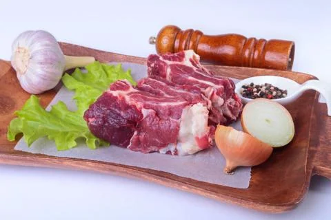 Raw beef edges, lettuce leaf, garlic, pepper grinder and spices on wooden desk Stock Photos