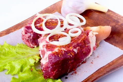 Raw beef edges, lettuce leaf, garlic, pepper grinder and spices on wooden desk Stock Photos