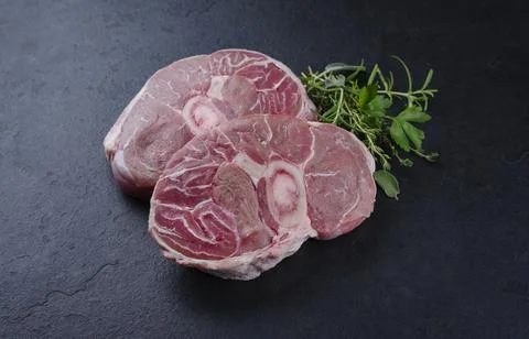 Raw beef leg slice with cross-section marbling with herbs and spices as ossob Stock Photos