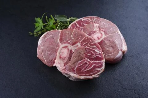Raw beef leg slice with cross-section marbling with herbs and spices as ossob Stock Photos