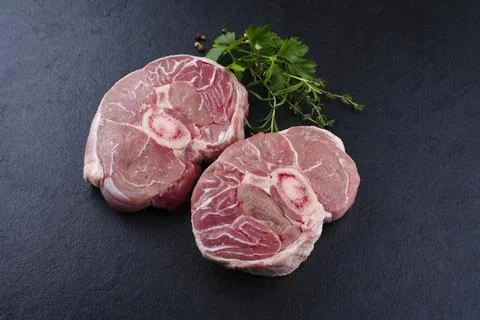 Raw beef leg slice with cross-section marbling with herbs and spices as ossob Stock Photos