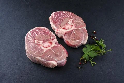 Raw beef leg slice with cross-section marbling as ossobuco offered with herbs Stock Photos