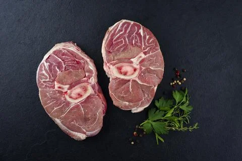 Raw beef leg slice with cross-section marbling with herbs and spices as ossob Stock Photos