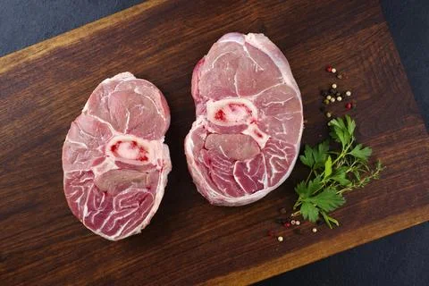 Raw beef leg slice with cross-section marbling with herbs and spices as ossob Stock Photos