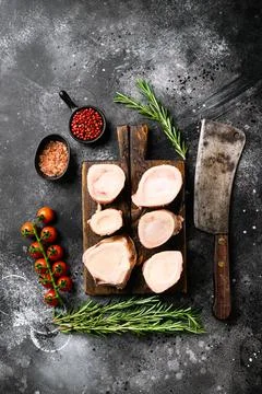 Raw beef marrow bones, on black dark stone table background, top view flat la Stock Photos