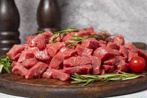 Raw beef meat chopped in cubes. Diced beef or lamb on a wooden serving board Stock Photos
