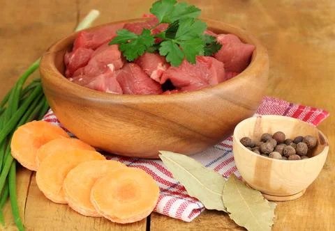 Raw beef meat with herbs and spices on wooden table on brown background Stock Photos