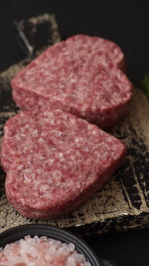 Raw beef or pork burger patty in the shape of a heart Video stock 300108580
