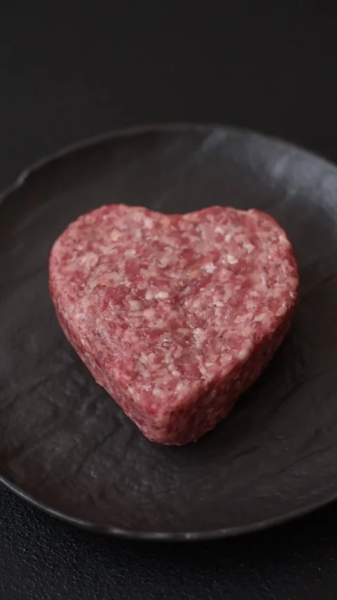 Raw beef or pork burger patty in the shape of a heart Video stock 300108585