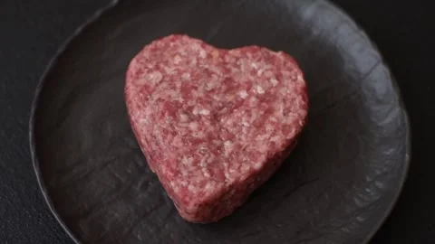 Raw beef or pork burger patty in the shape of a heart Video stock 300108586