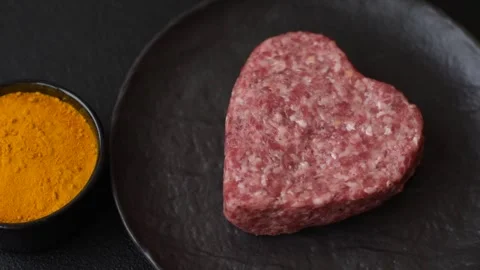 Raw beef or pork burger patty in the shape of a heart Video stock 300108589