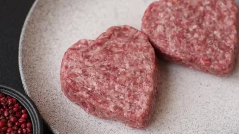 Raw beef or pork burger patty in the shape of a heart Video stock 300108597