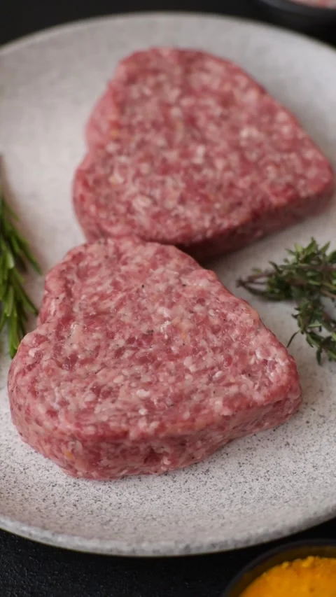 Raw beef or pork burger patty in the shape of a heart Video stock 300108599