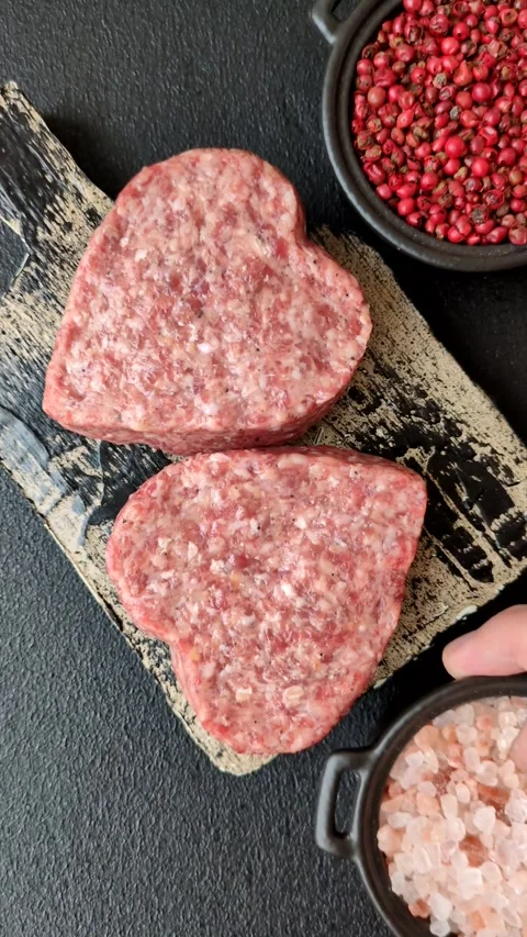 Raw beef or pork burger patty in the shape of a heart Video stock 300108662