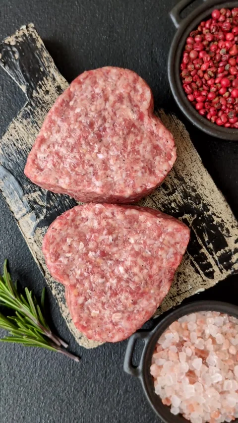 Raw beef or pork burger patty in the shape of a heart Video stock 300108680