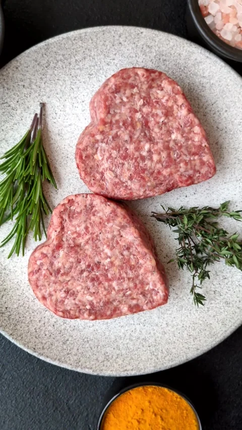 Raw beef or pork burger patty in the shape of a heart Video stock 300108697
