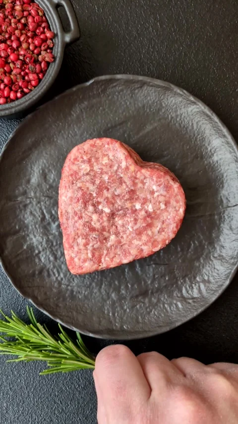 Raw beef or pork burger patty in the shape of a heart Video stock 300108698