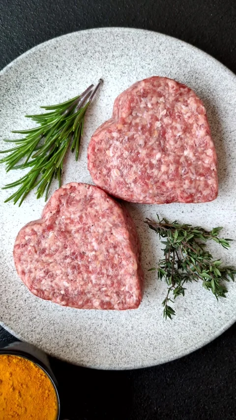 Raw beef or pork burger patty in the shape of a heart Video stock 300108702