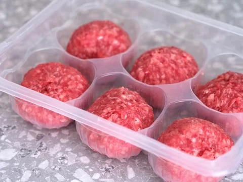 Raw beef patties in a plastic container. Stock Photos