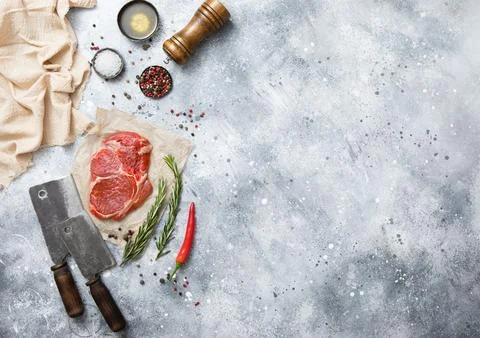 Raw beef rib eye steak on with meat cleaver on light kitchen table background Stock Photos
