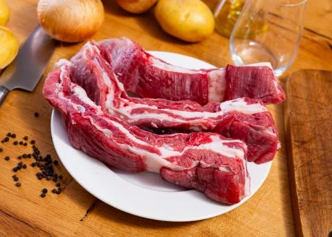 Raw beef ribs on the kitchen table along with other ingredients for making Stock Photos