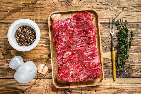 Raw beef round cut meat on a wooden tray with herbs. wooden background. Top view Stock Photos