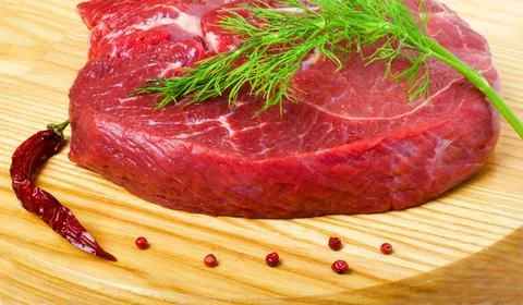 Raw beef steak and chilli pepper on wooden board, close up Stock Photos