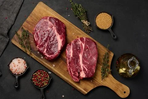 Raw beef steak chuck eye roll on wooden board. Spices for cooking Himalayan.. Stock Photos