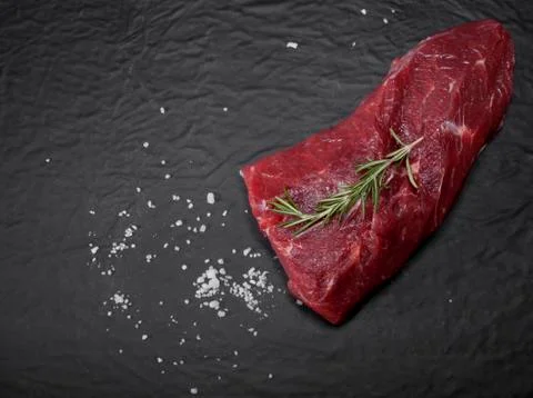Raw beef steak on a cutting board with rosemary and spices. Foto stock