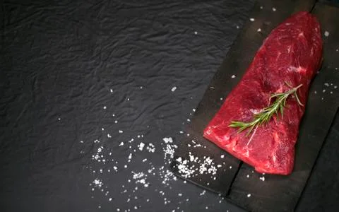 Raw beef steak on a cutting board with rosemary and spices. Stock Photos