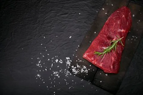 Raw beef steak on a cutting board with rosemary and spices. Stock Photos