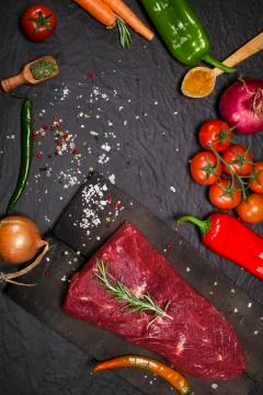 Raw beef steak on a cutting board with rosemary and spices. Stock Photos