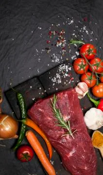 Raw beef steak on a cutting board with rosemary and spices. Stock Photos