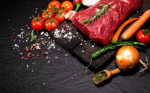 Raw beef steak on a cutting board with rosemary and spices. Stock Photos