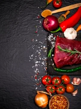 Raw beef steak on a cutting board with rosemary and spices. Stock Photos