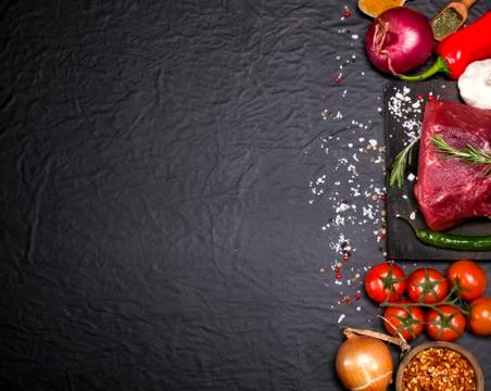 Raw beef steak on a cutting board with rosemary and spices. Stock Photos