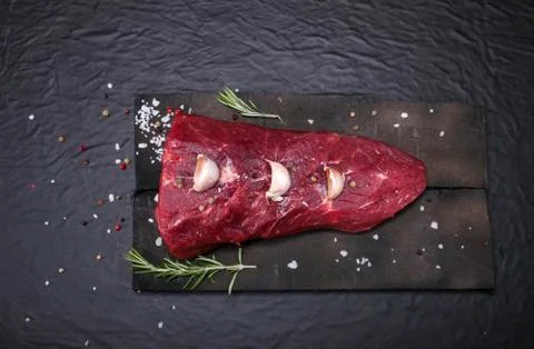 Raw beef steak on a cutting board with rosemary and spices. Stock Photos