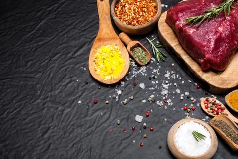 Raw beef steak on a cutting board with rosemary and spices. Stock Photos