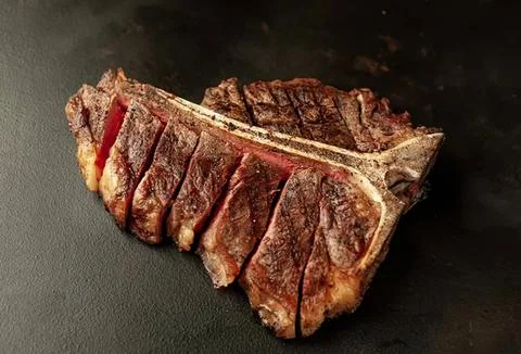 Raw beef steak on dark background with slices Stock Photos