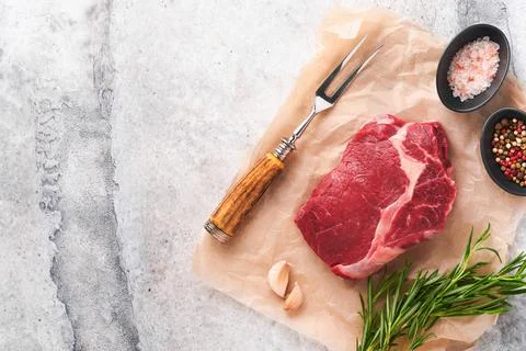 Raw beef steak. Fresh beef rib eye steak with fork rosemary, salt and pepper  Stock Photos
