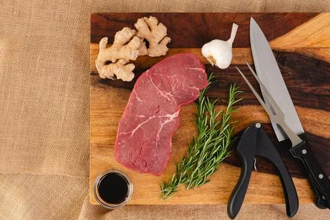Raw beef steak with ginger root, garlic, soy sauce, and rosemary close-up o.. Stock Photos